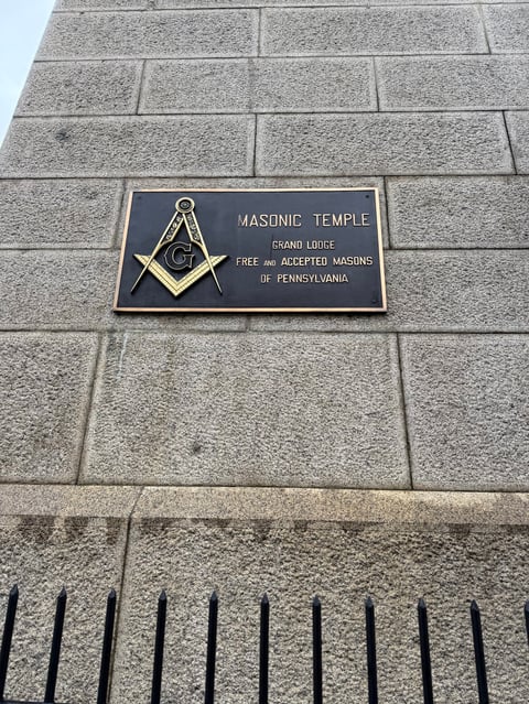 Bronze plaque reading Masonic Temple on gray stone building facade with Masonic symbol