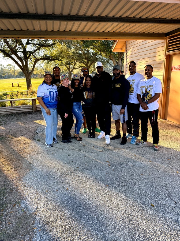 Group of diverse people standing together outside a building with open fields and trees in the background